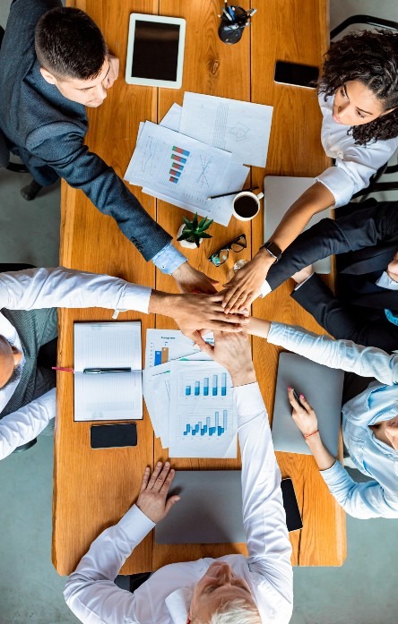 united-colleagues-holding-hands-sitting-at-desk-in-2023-11-27-05-19-45-utc